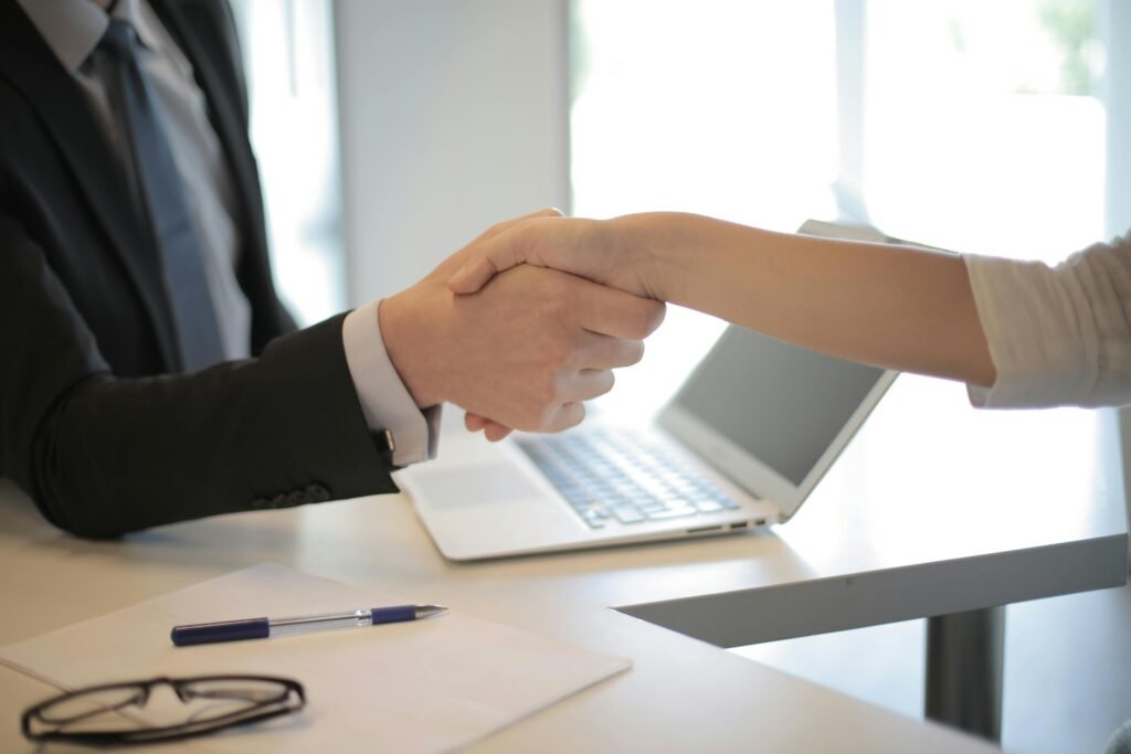 outplacement-reims Close-up of a professional handshake over a laptop during a business meeting in an office.