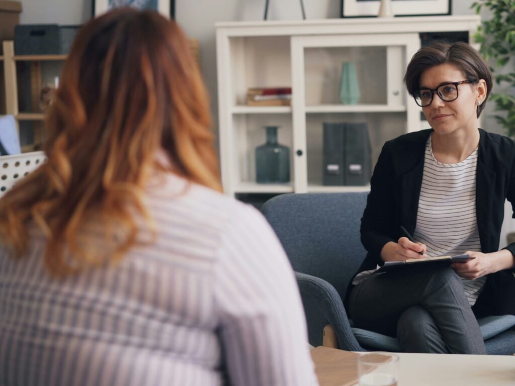 un coach professionnel prend des notes assis face à son client